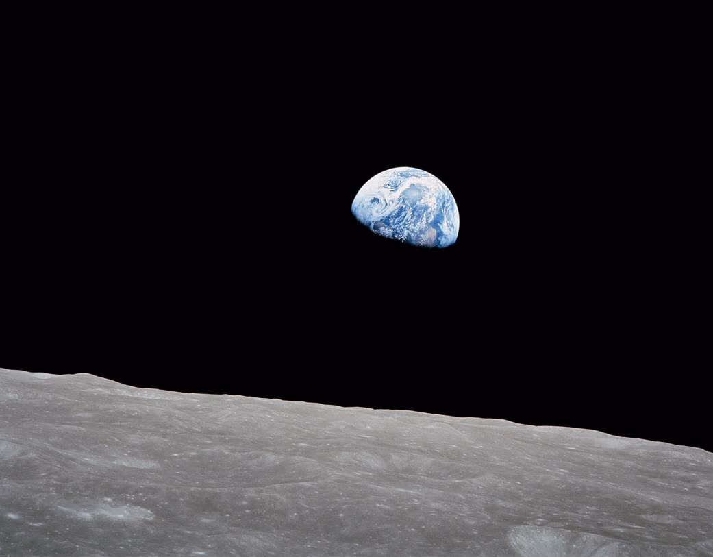 Earth, a blue and white crescent, rising above the grey horizon of the Moon against black space, photographed by the Apollo 8 crew in December 1968.